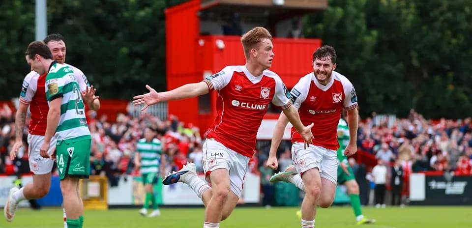 Player celebrating a goal with teammates on pitch