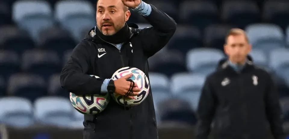 Coach directing players while holding footballs