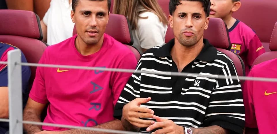 Two men seated in stadium watching match
