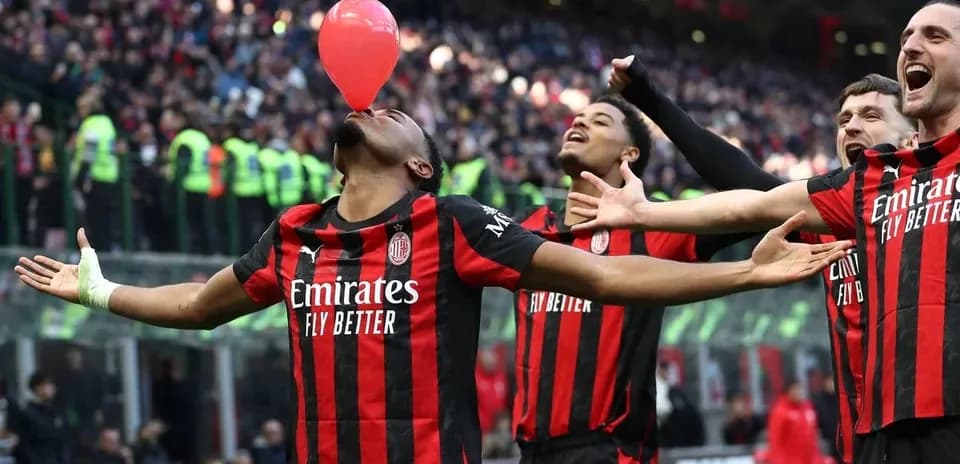AC Milan players celebrating with a balloon on pitch