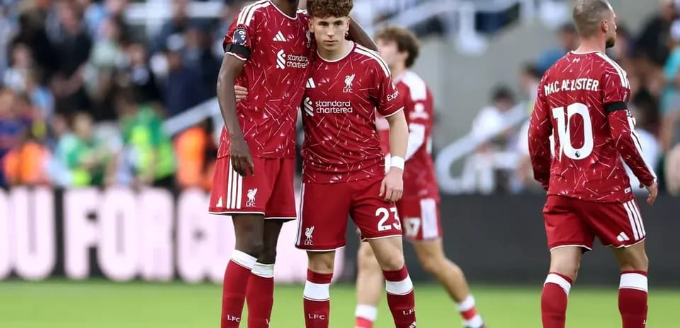 Two Liverpool players in red kits on field