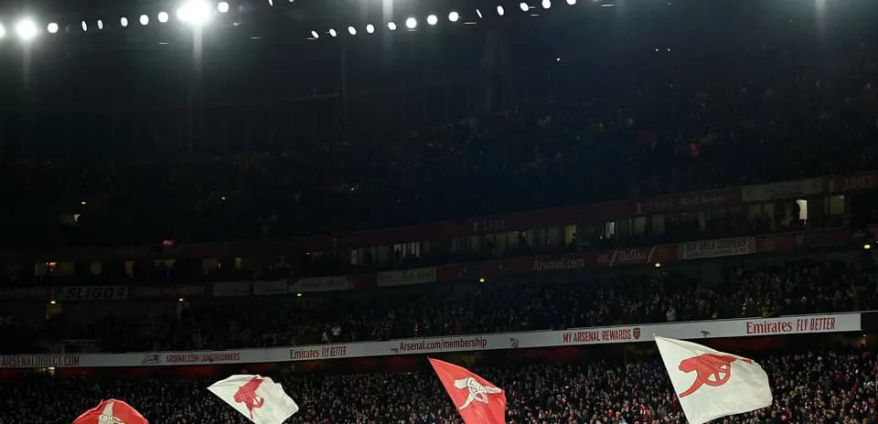 Fans waving Arsenal flags in crowded stadium