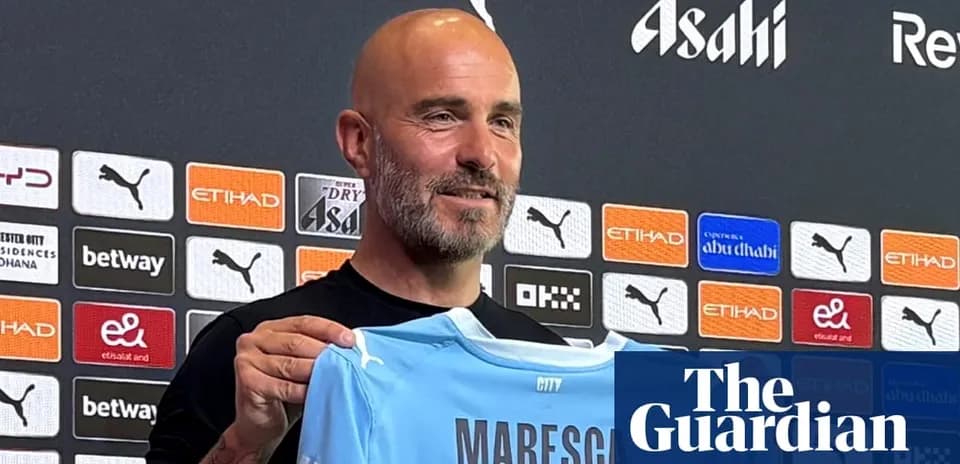 Manager holding Manchester City jersey at press conference