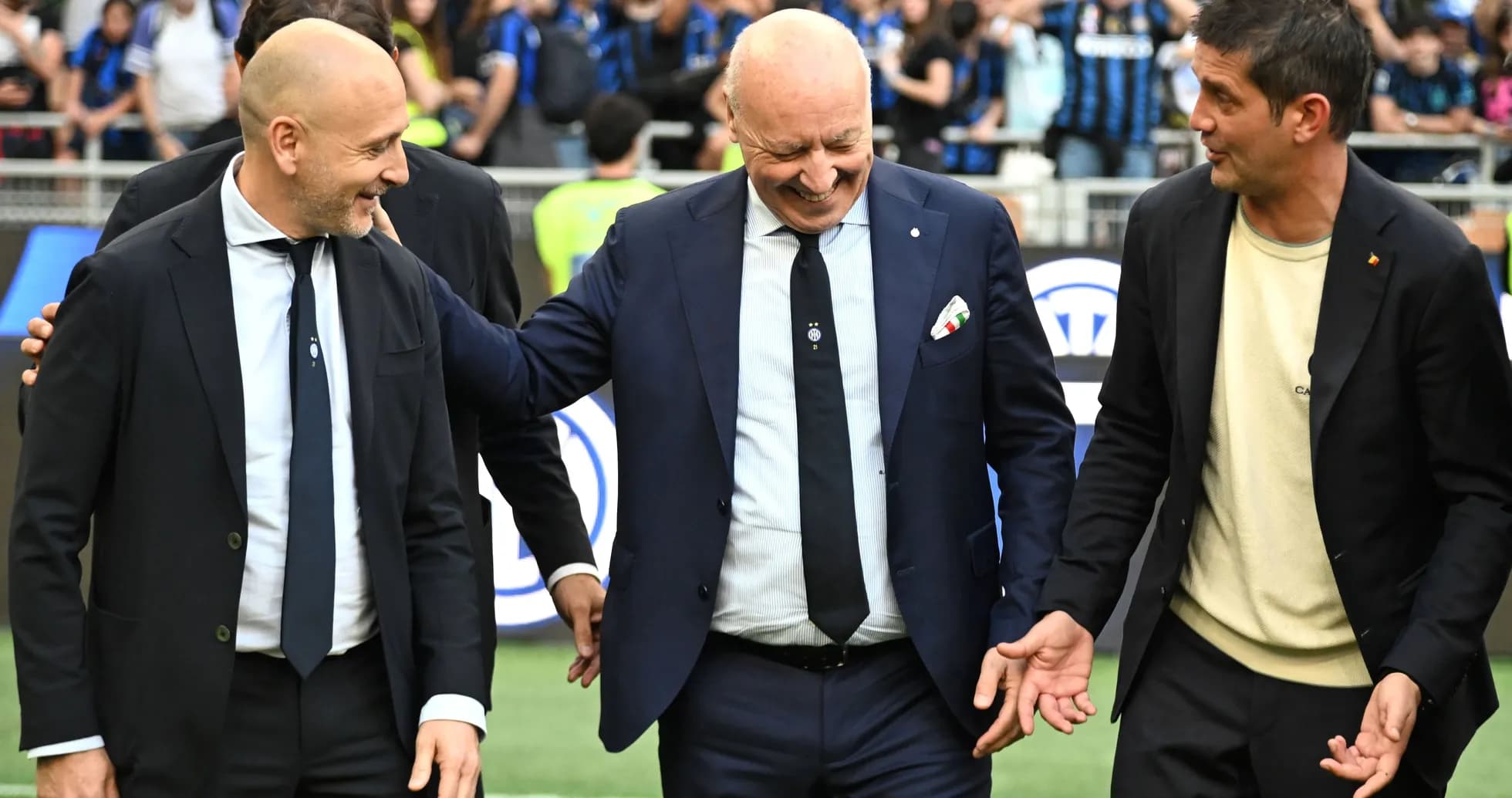 Three coaches interacting on the pitch before a match