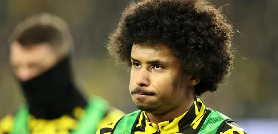 Player in yellow and green kit during match warm-up