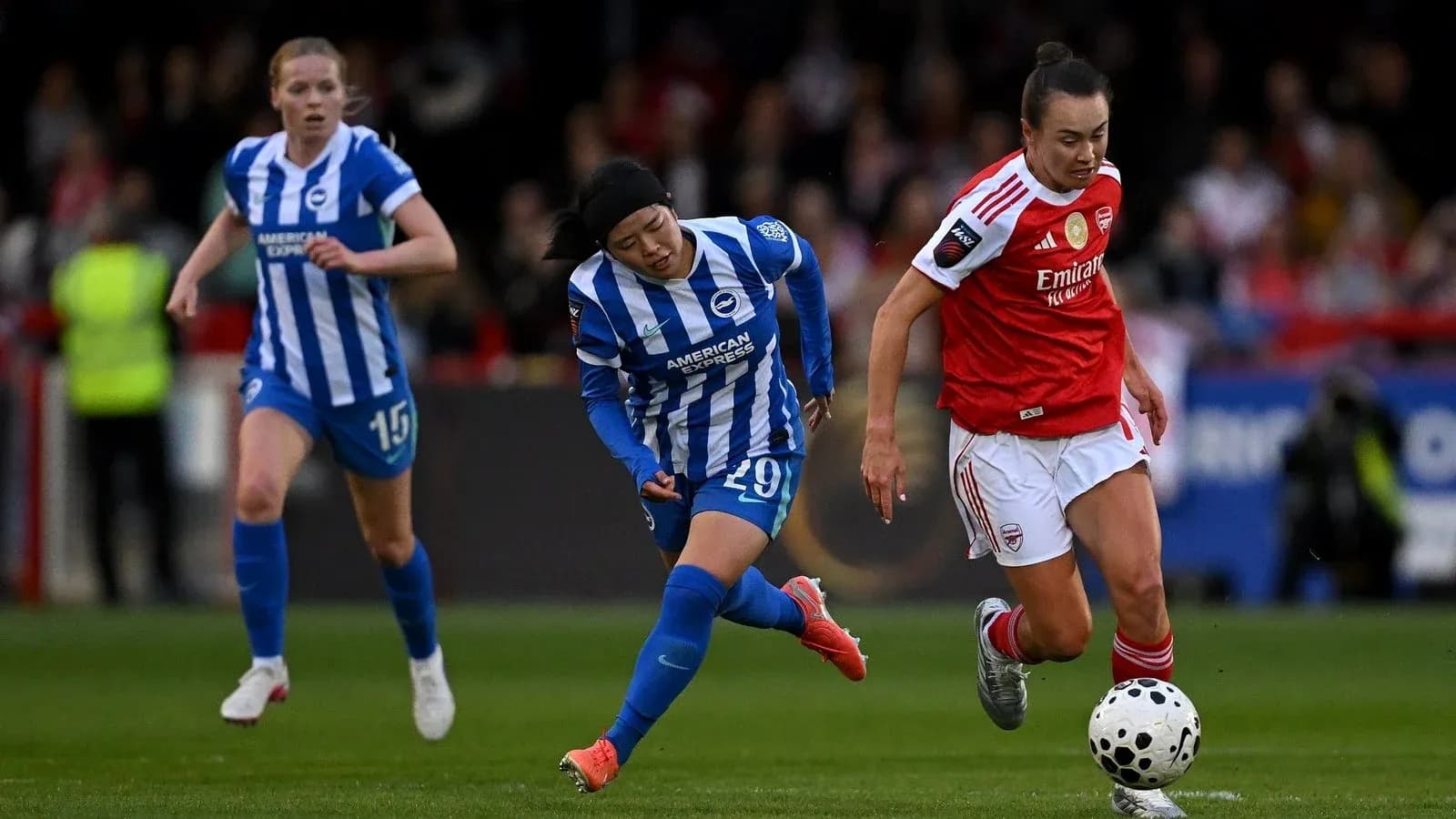 Arsenal player dribbling past Brighton defenders during match
