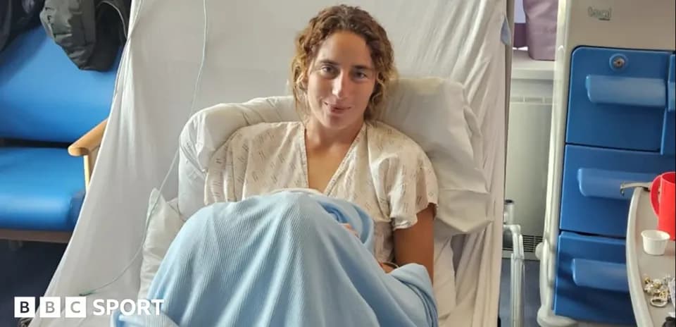 Athlete sitting in hospital bed wearing gown