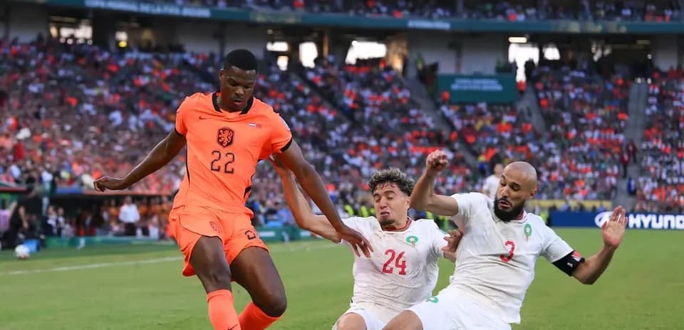 Player in orange jersey dribbling past two defenders