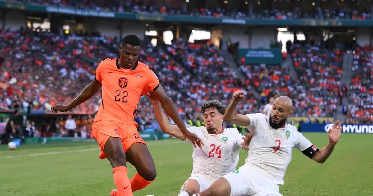 Player in orange jersey dribbling past two defenders