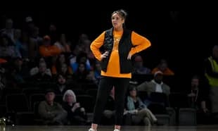Woman in orange shirt and black vest on court