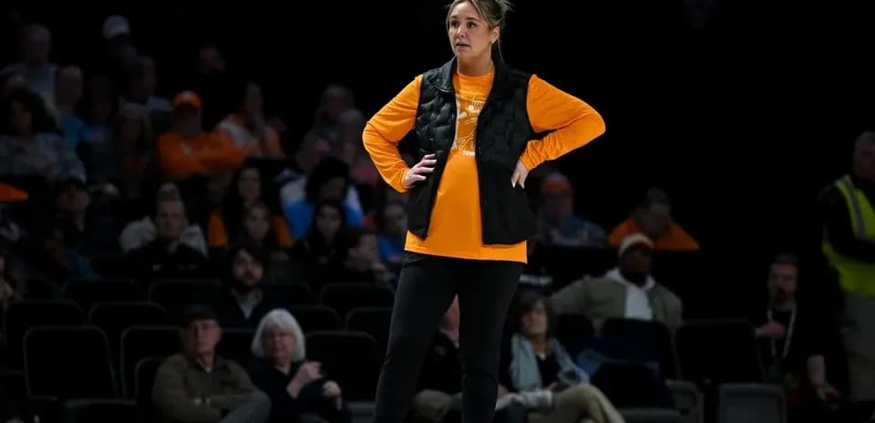 Woman in orange shirt and black vest on court