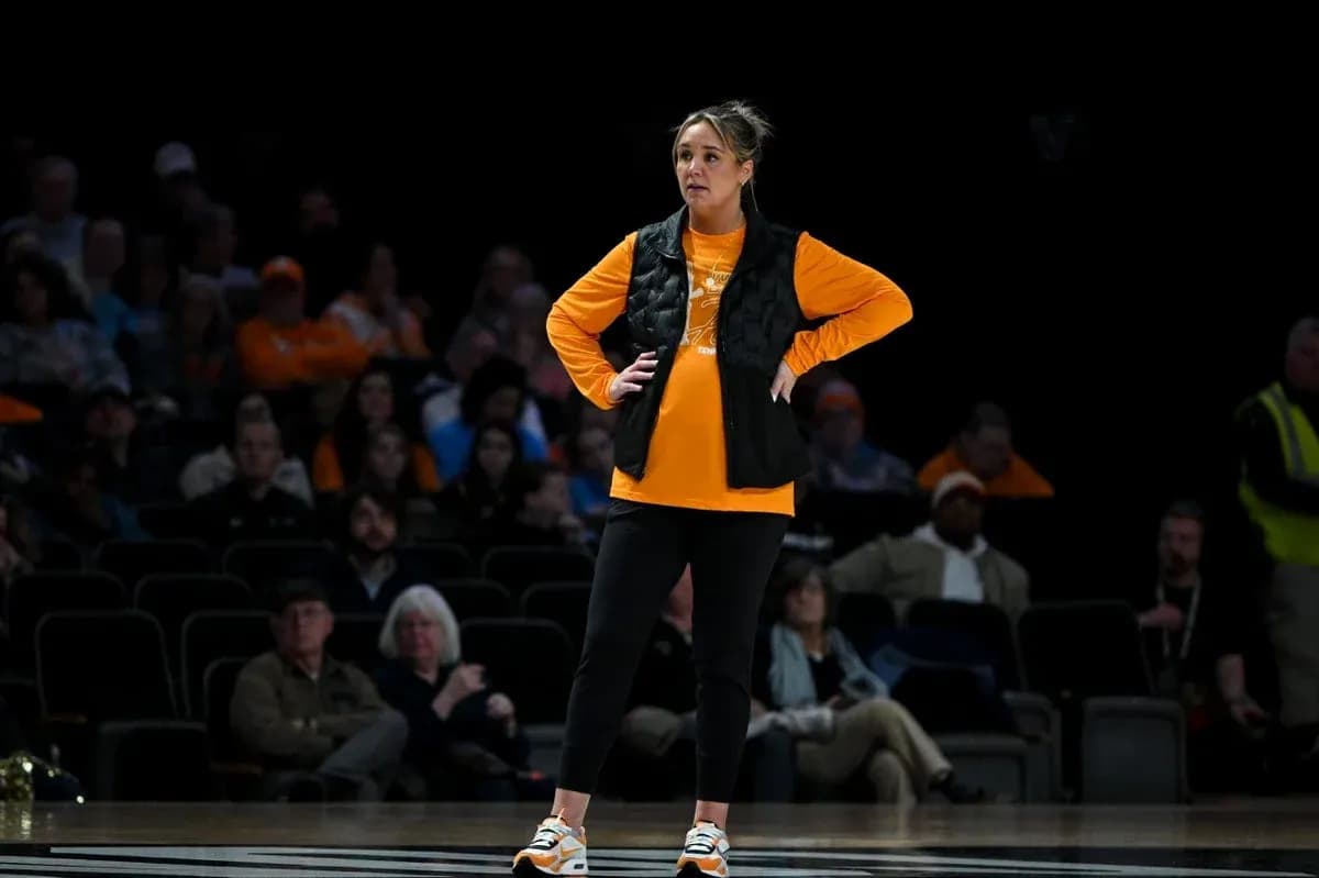 Woman in orange shirt and black vest on court