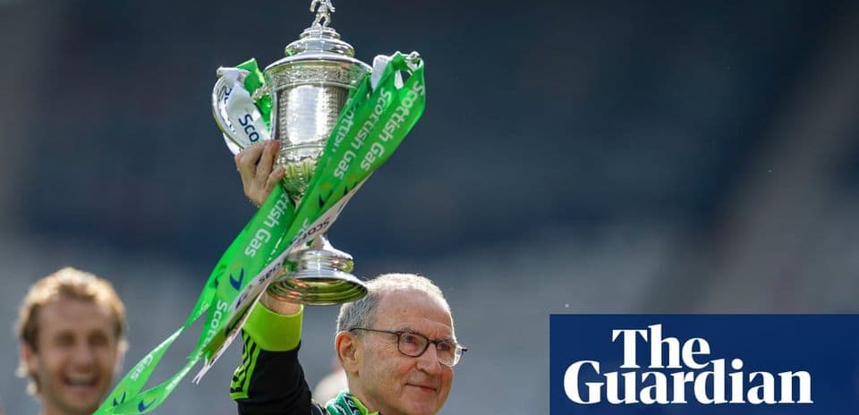 Coach holding trophy with green ribbons aloft