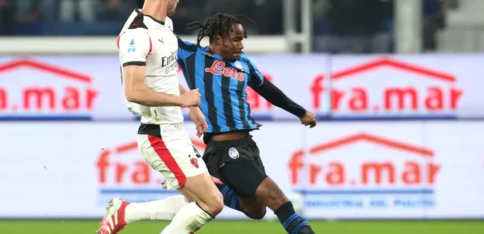 AC Milan player challenges Atalanta player for the ball