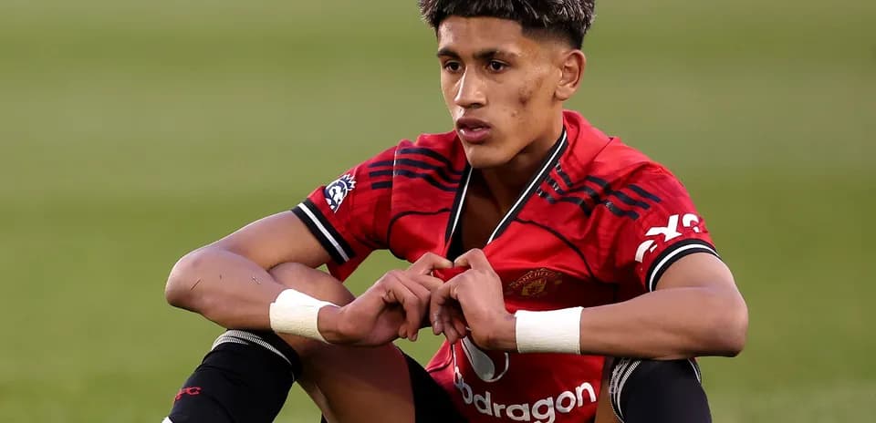 Player sitting on field in Manchester United jersey