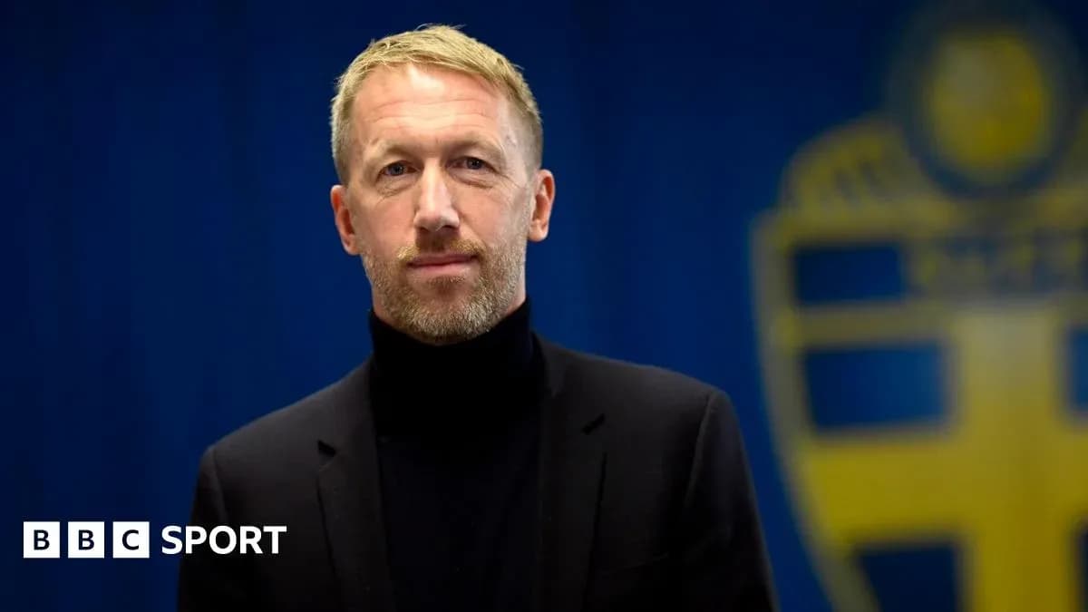 Man in black suit standing in front of blue background