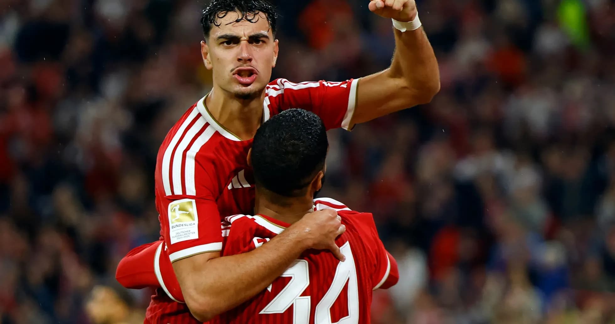 Player celebrating a goal with teammate in stadium