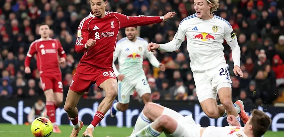 Liverpool player dribbling past Leeds defenders during match