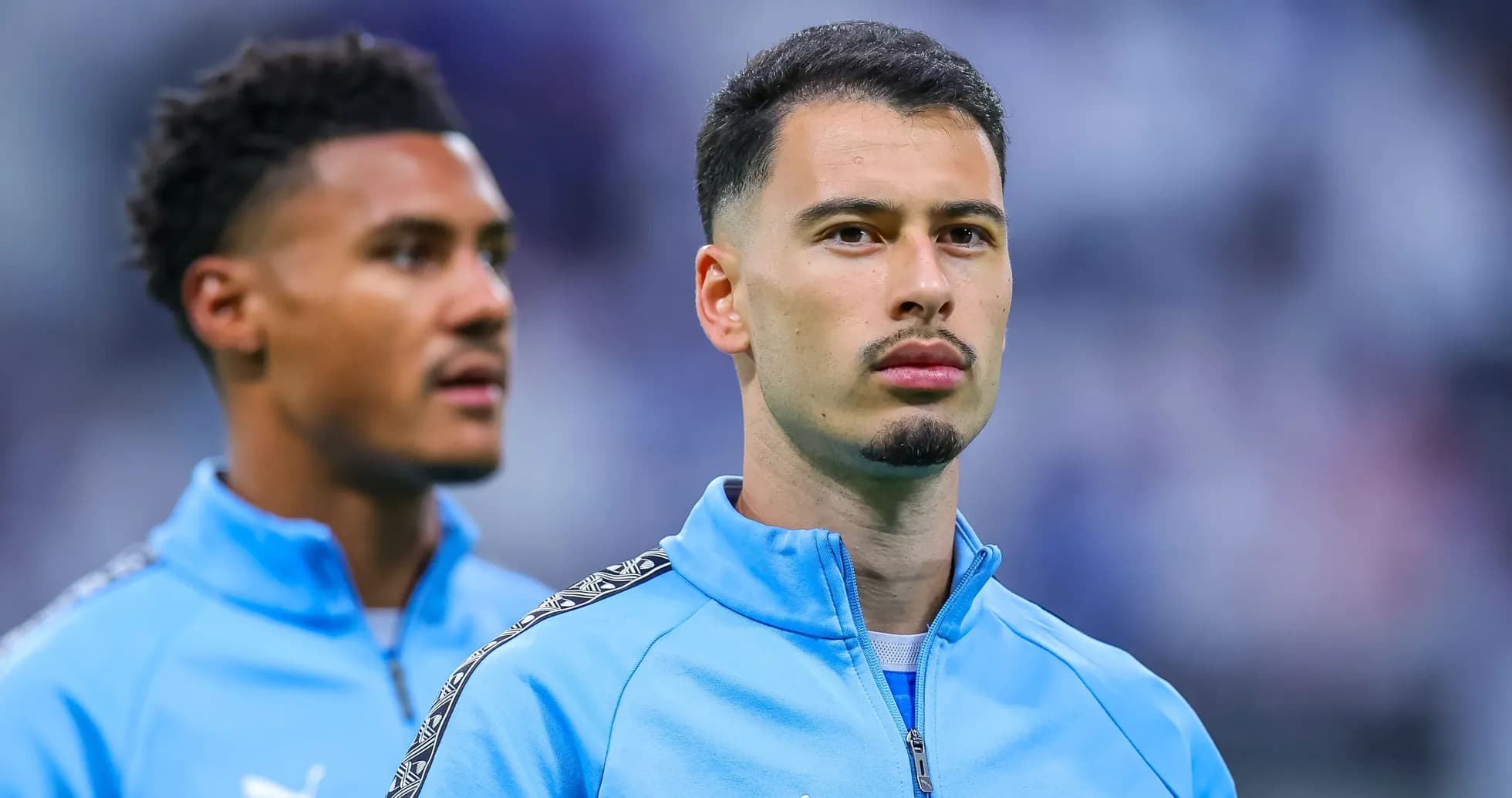 Two players in blue training jackets on pitch