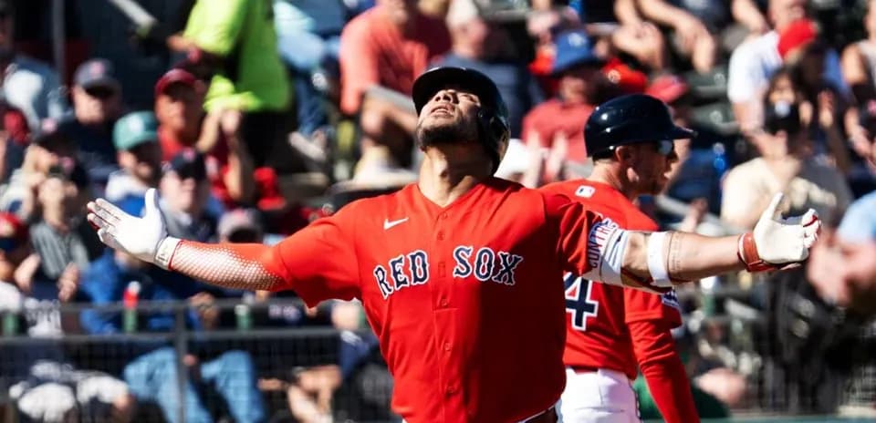 Red Sox player celebrating a hit with fans in background