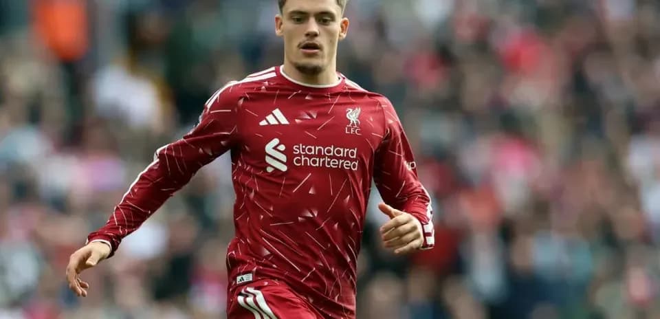 Player running on field wearing Liverpool jersey