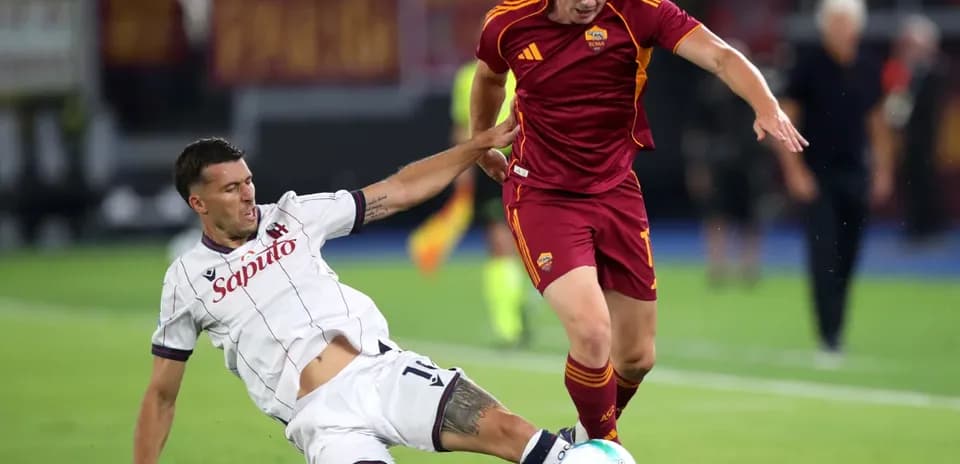 Bologna player tackling AS Roma opponent