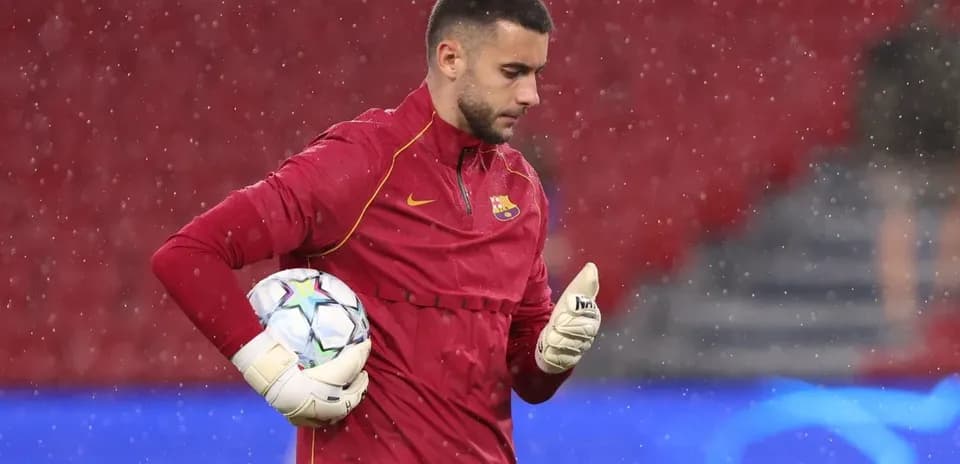 Goalkeeper in red training gear holding a ball