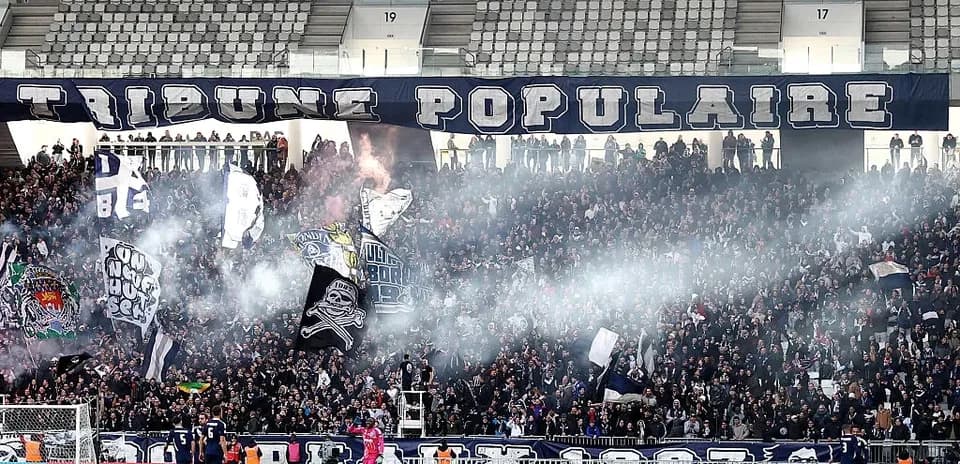 Crowd with flags and smoke in stadium stands