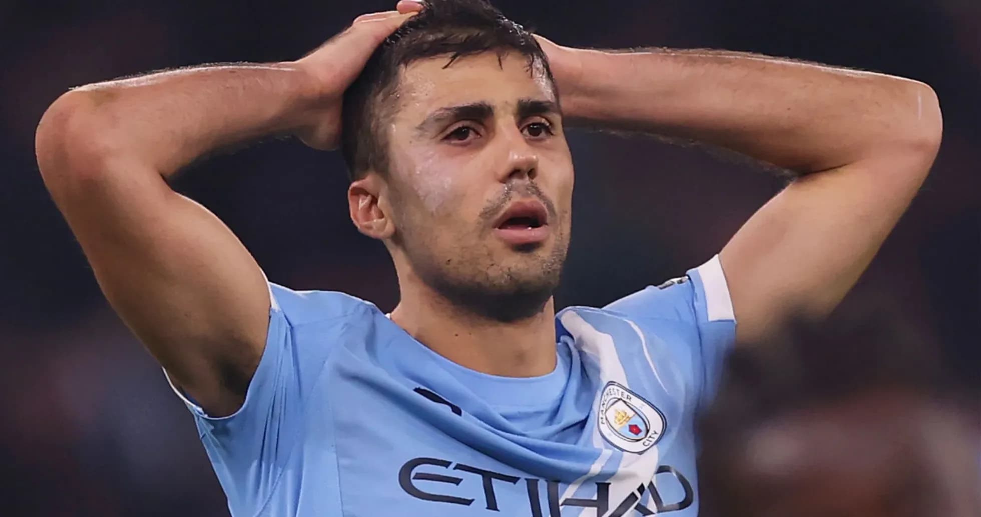 Player in Manchester City jersey with hands on head