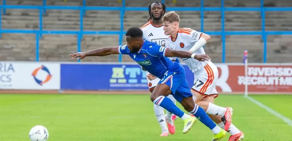 Player in blue jersey attempting to evade two defenders