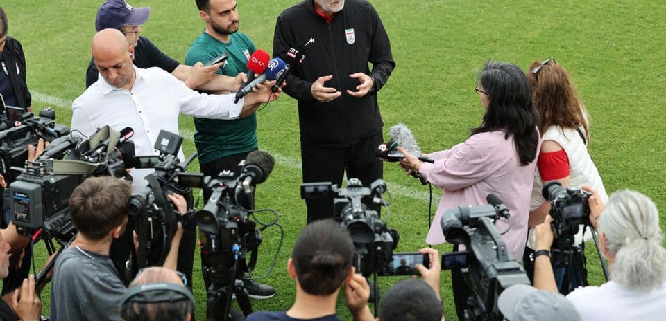 Coach addressing media during press conference on field