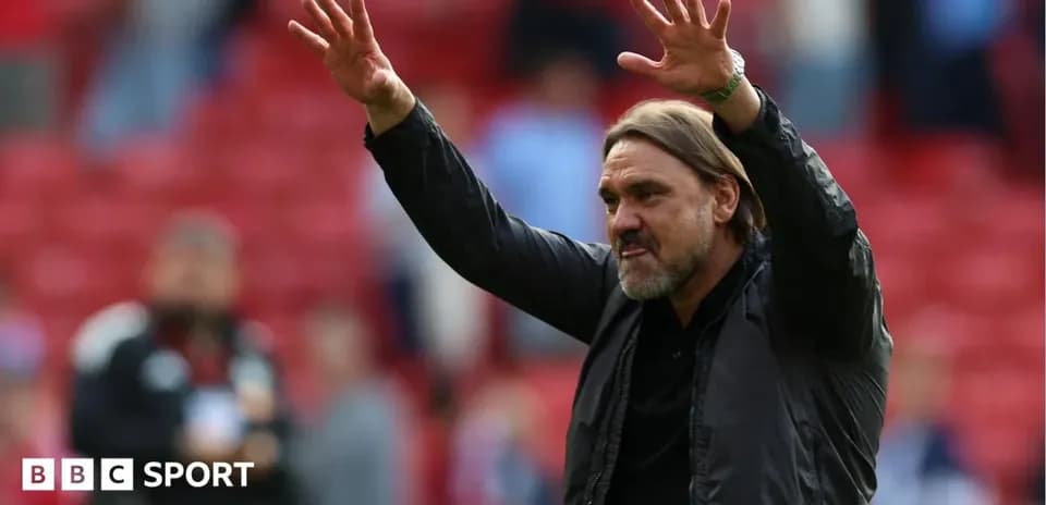 Manager gesturing to fans in stadium