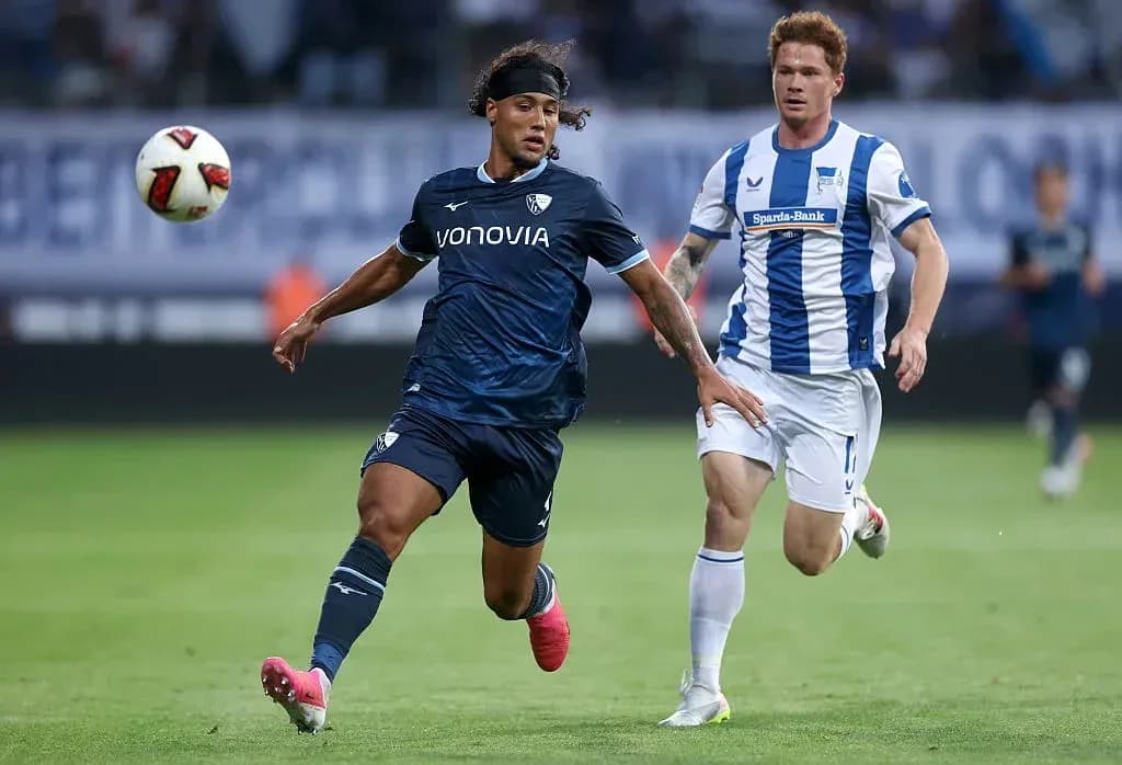 Player in blue running with the ball, defender chasing