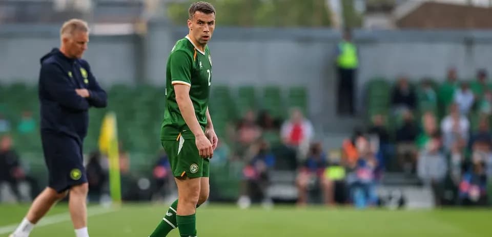 Player in green jersey on field with coach nearby