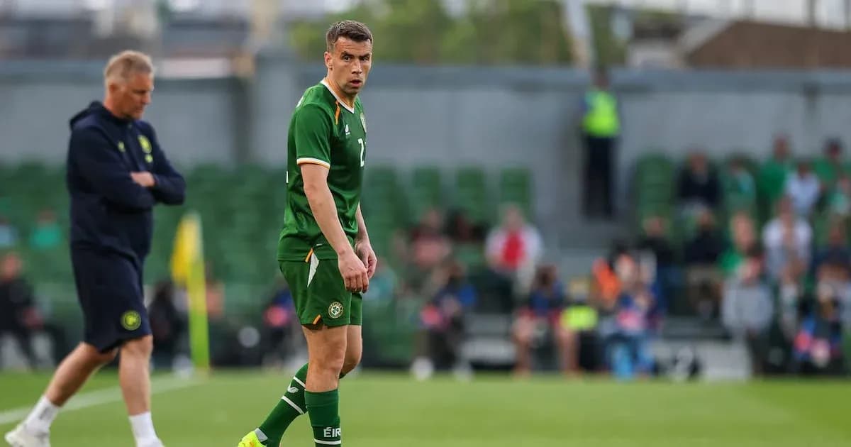 Player in green jersey on field with coach nearby