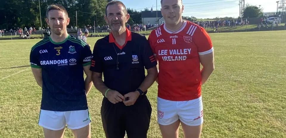Two players and a referee posing on field