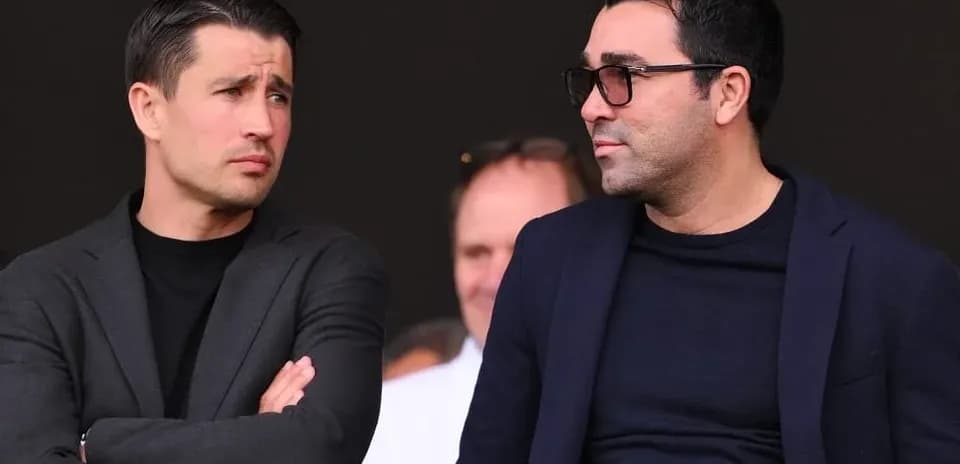 Two men conversing in a stadium setting