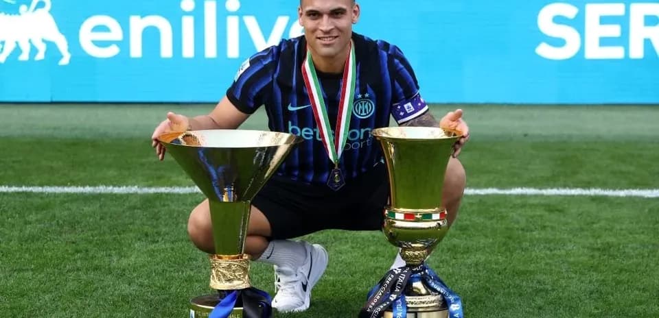 Player posing with two trophies on the field