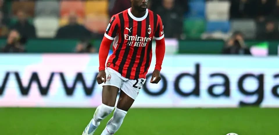 Player in AC Milan kit dribbling ball on field