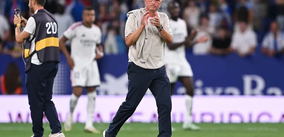 Coach applauding during a match with players in background