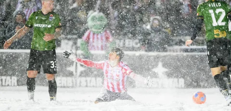 Players competing in snow during match Players competing in snow during match