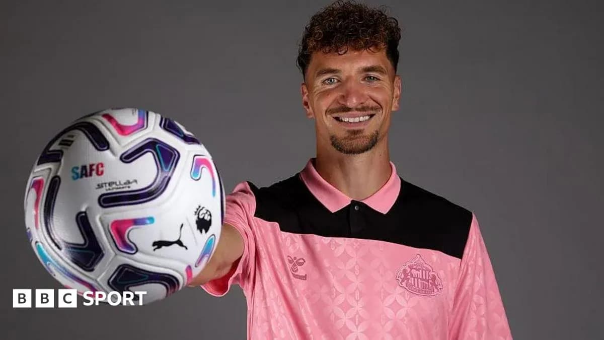 Player holding a football, wearing pink kit Player holding a football, wearing pink kit