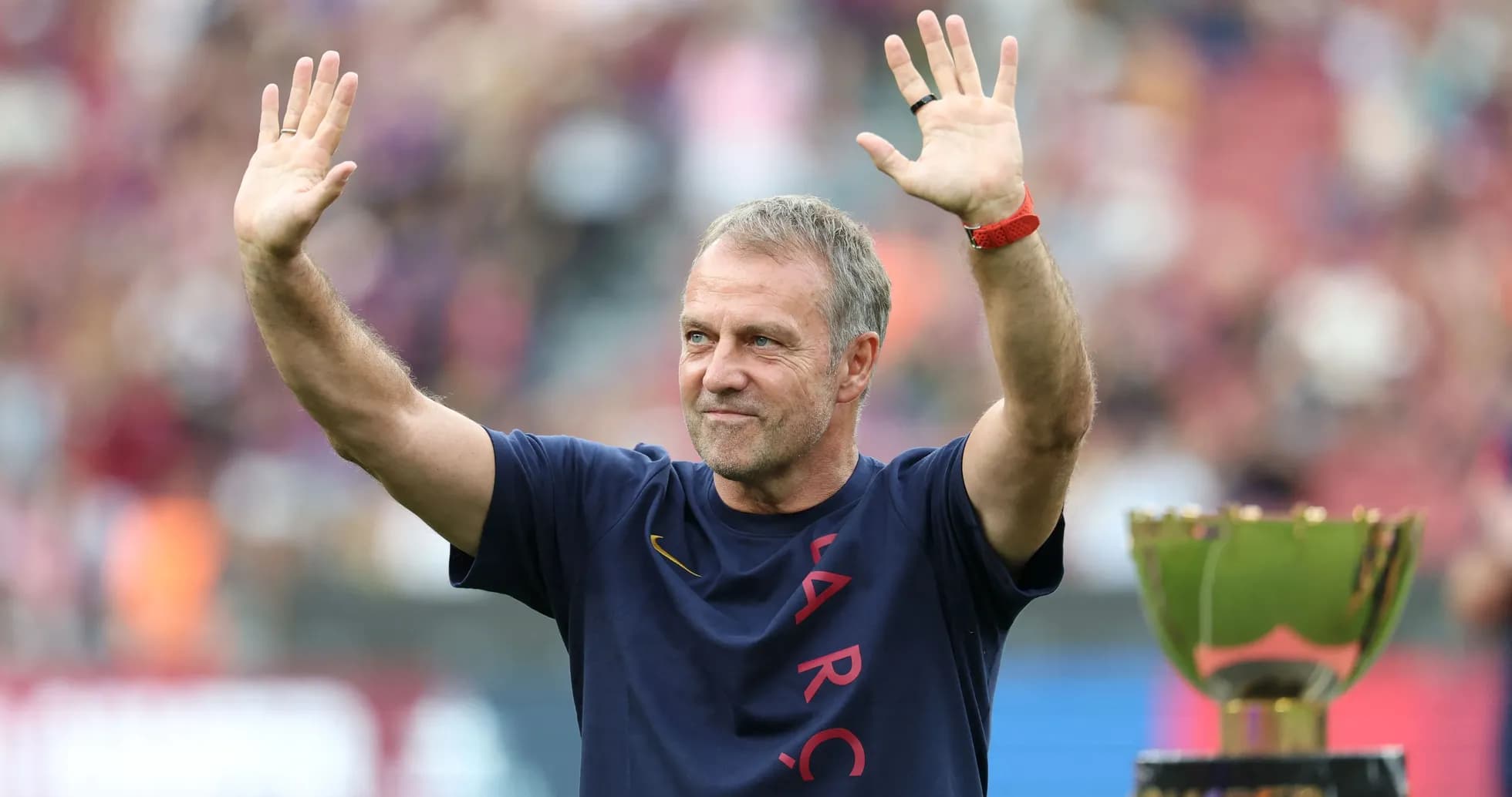 Coach waving to fans beside a trophy Coach waving to fans beside a trophy
