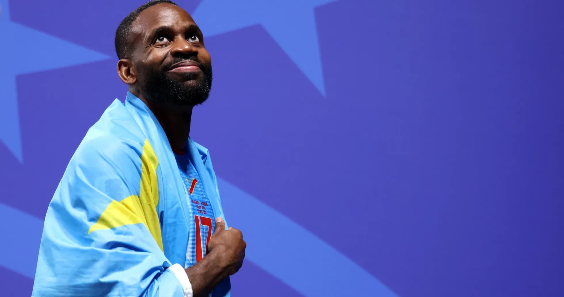 Athlete wearing national flag, smiling during event Athlete wearing national flag, smiling during event