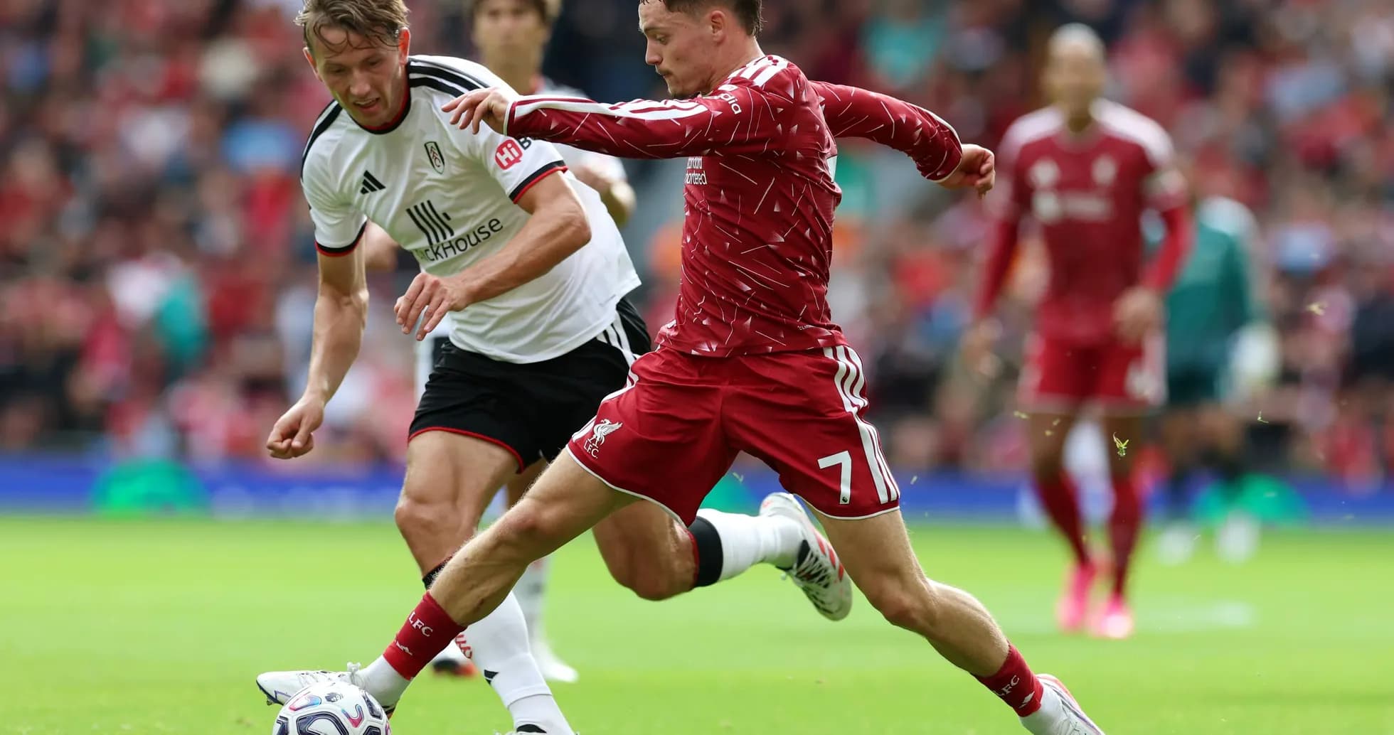 Liverpool player challenging Fulham opponent for the ball Liverpool player challenging Fulham opponent for the ball