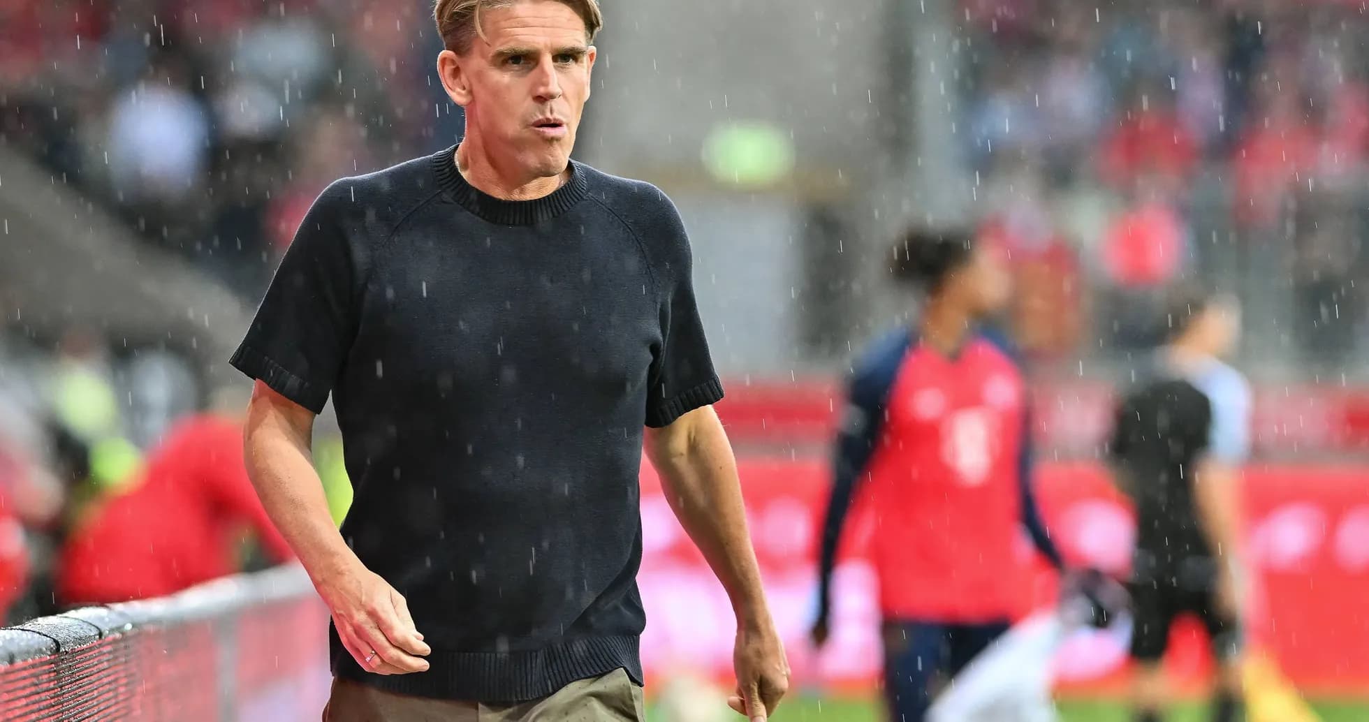Coach walking on sideline during rainy match Coach walking on sideline during rainy match