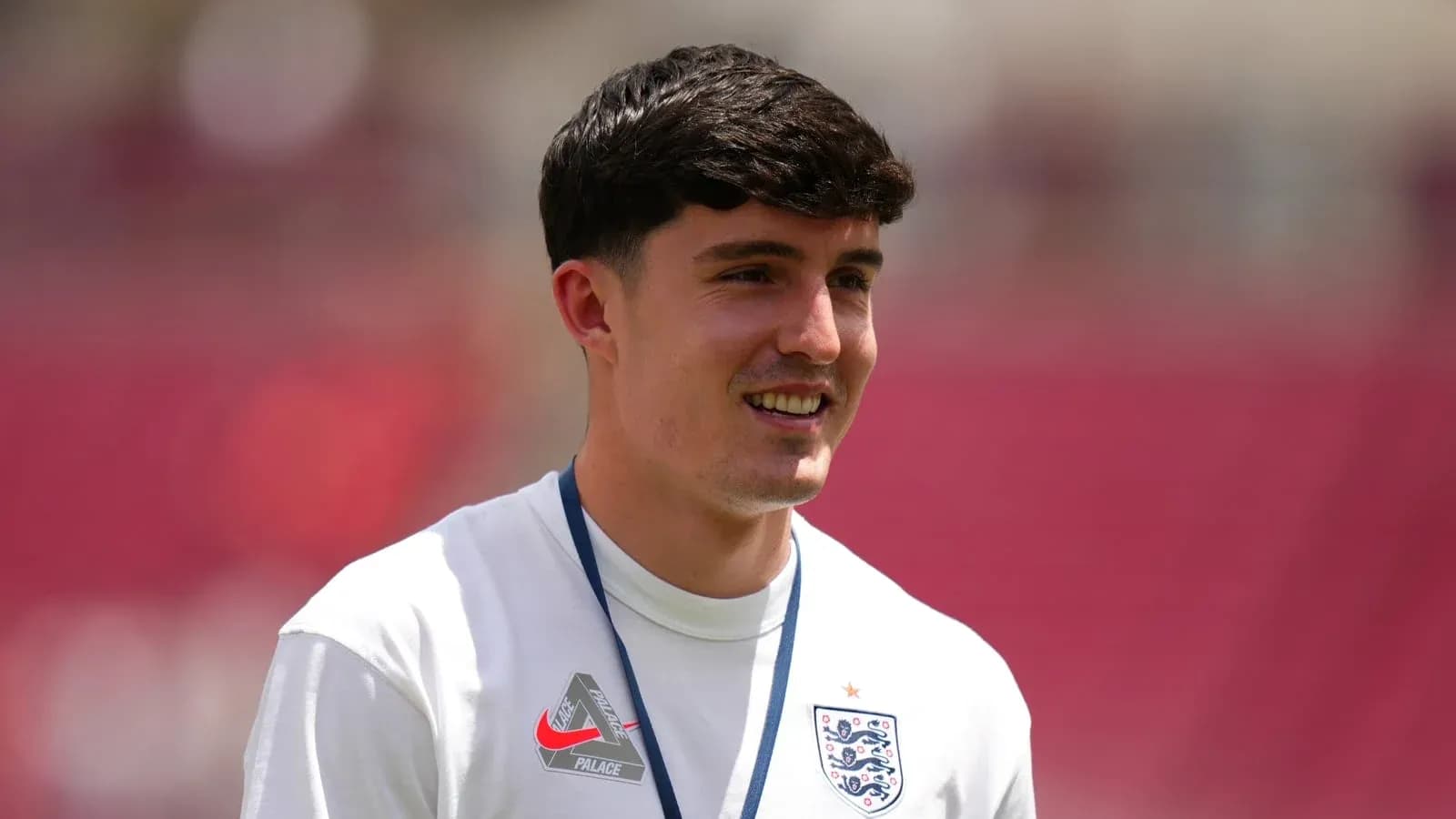 Player in England training kit smiling on pitch Player in England training kit smiling on pitch