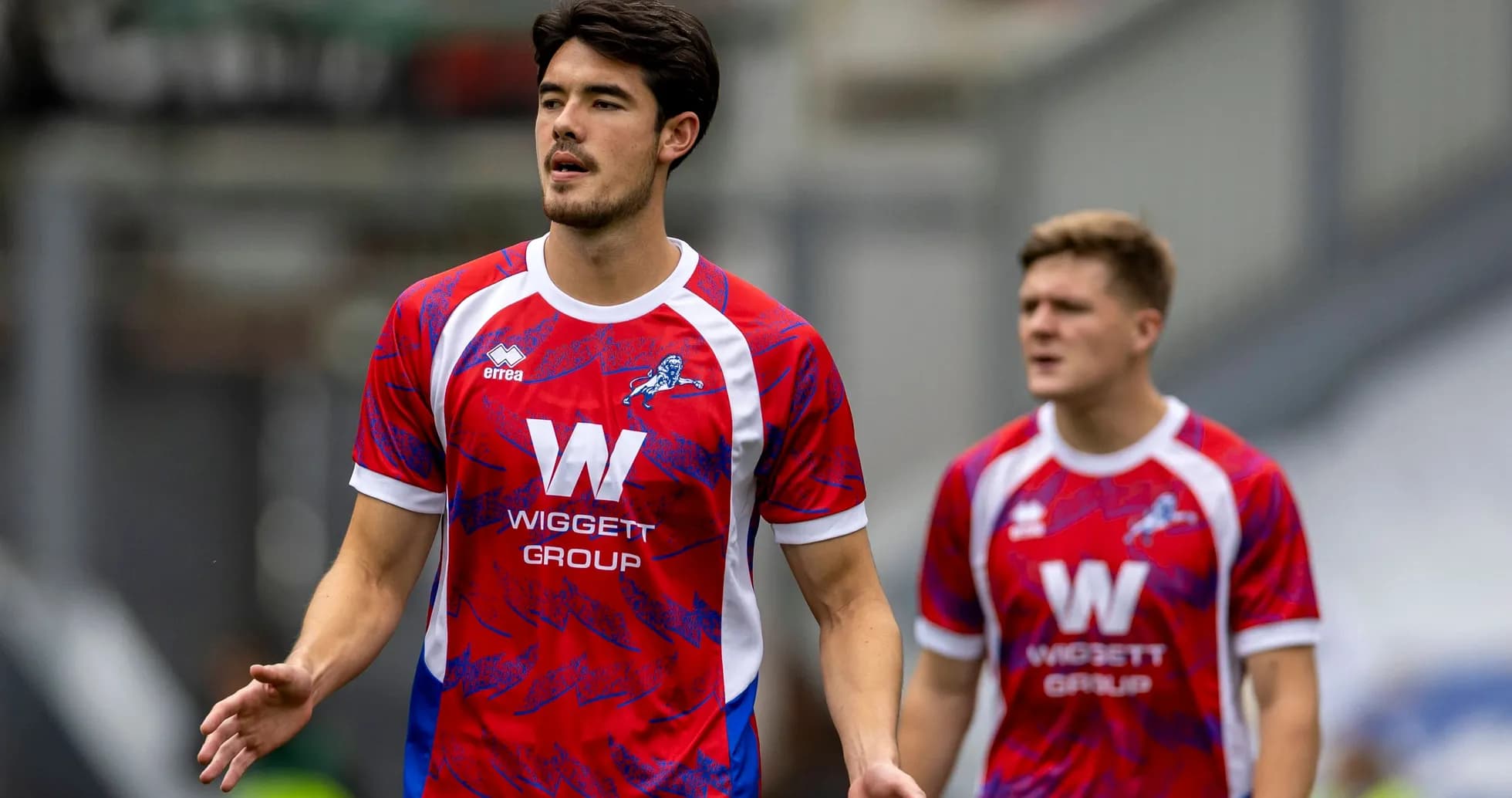 Two players in red and blue football kits walking Two players in red and blue football kits walking
