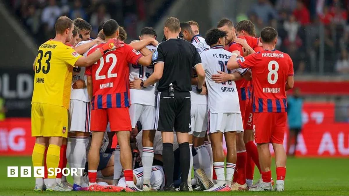 Players from both teams gathered around an injured player Players from both teams gathered around an injured player