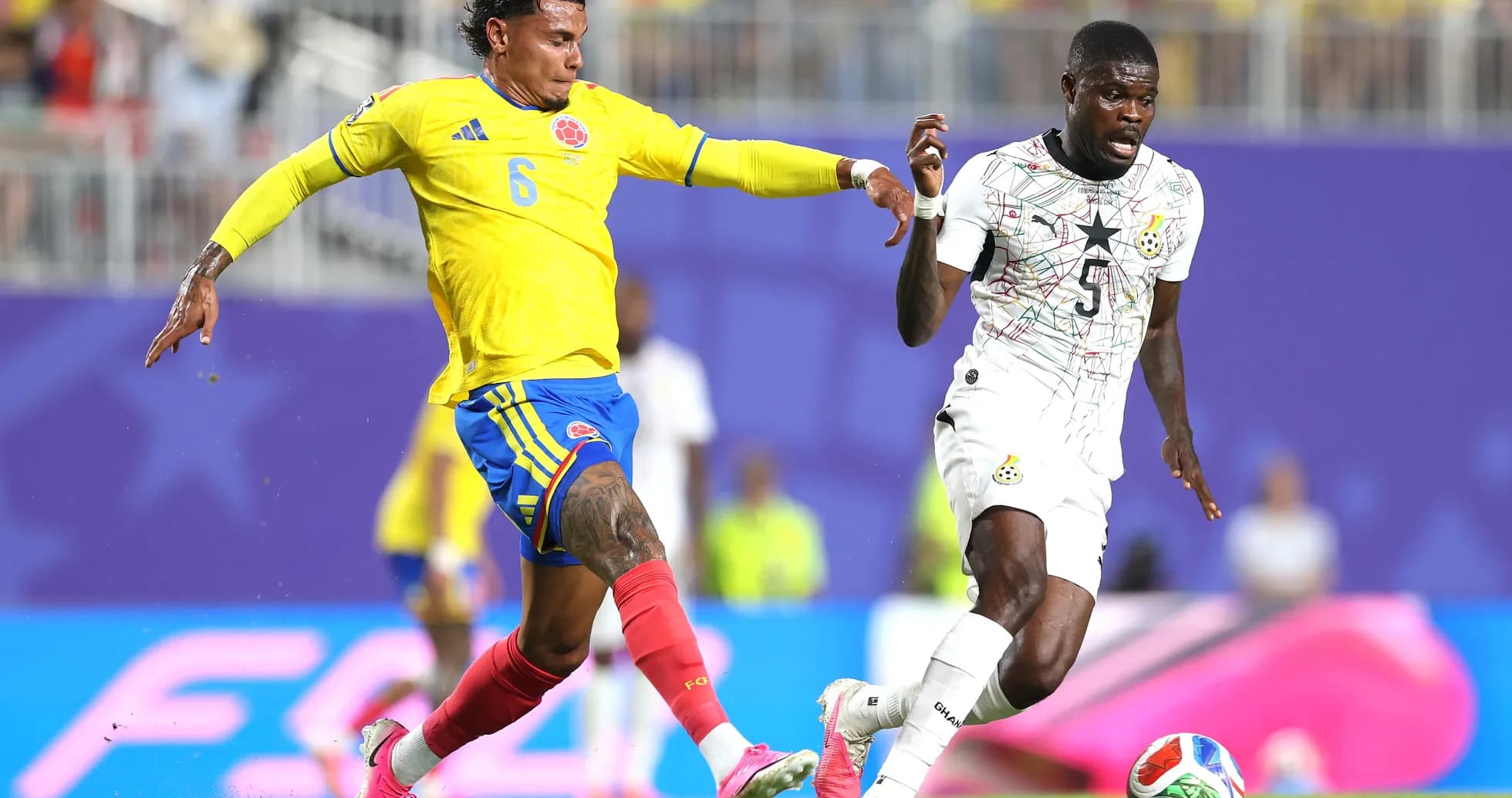 Colombian player challenges Ghanaian opponent during match Colombian player challenges Ghanaian opponent during match